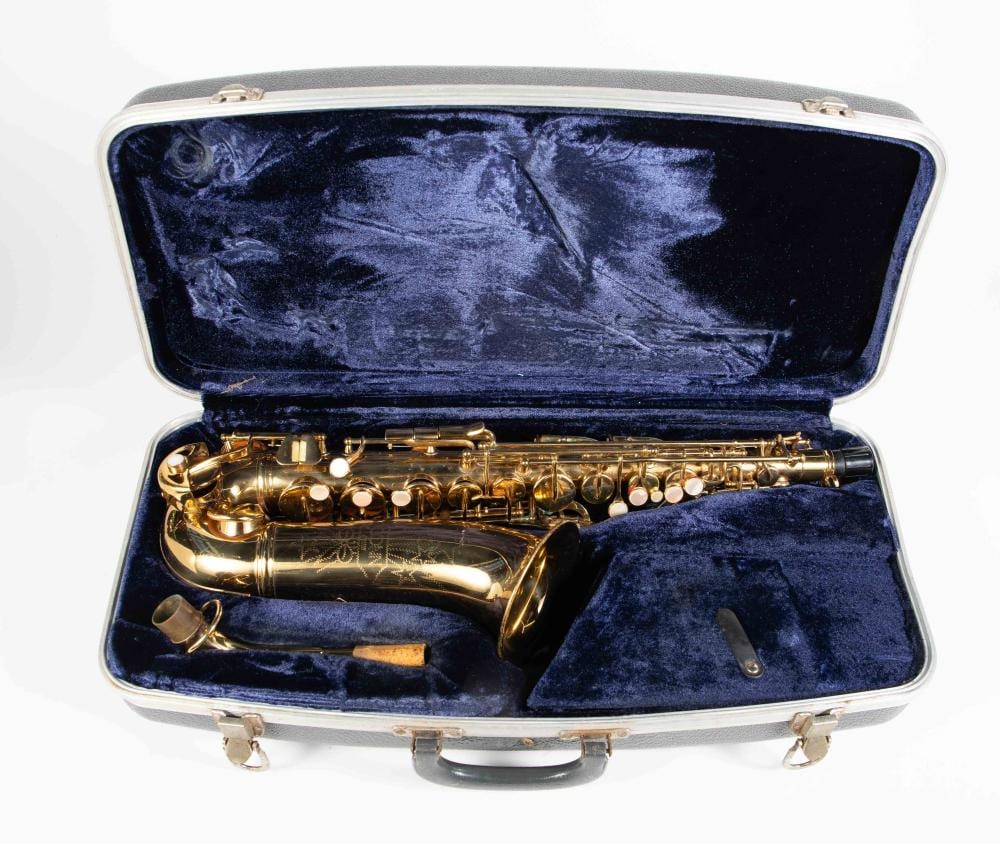 Gold saxophone resting inside a blue velvet-lined hard case with the lid open.