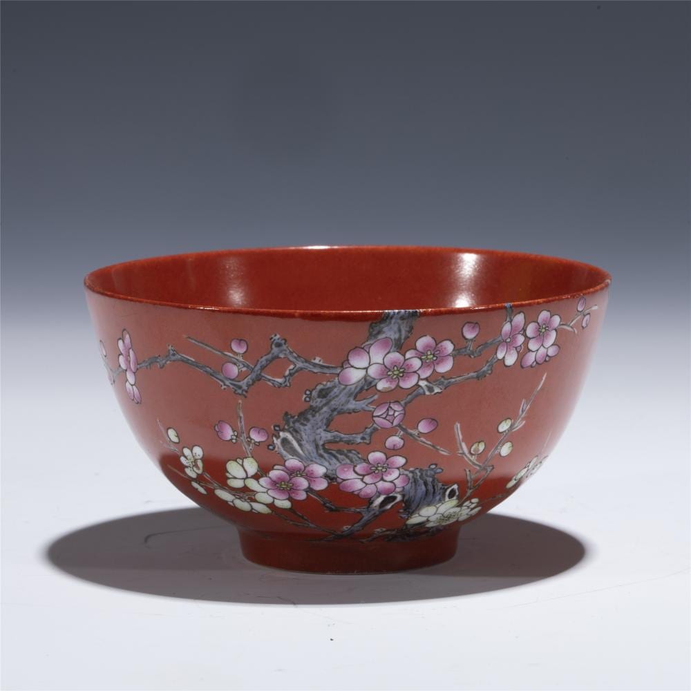 Red ceramic bowl with wide rim, decorated with pink and white blossoms on branching gray stems.