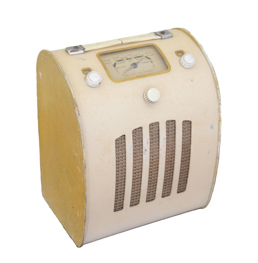 Vintage beige bakelite-style radio with a rectangular dial window, four vertical speaker grille bars, and four round knobs on the front.