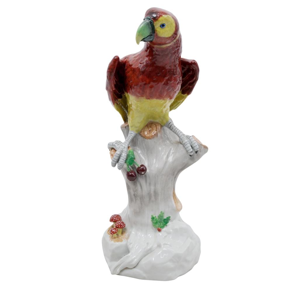Colorful porcelain parrot figurine perched on a white branch-like base with painted fruit and foliage accents.