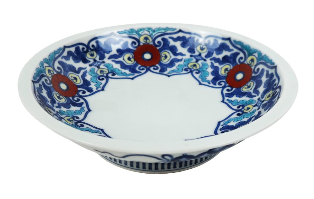 White shallow porcelain bowl with blue and red decorative border pattern around the rim.