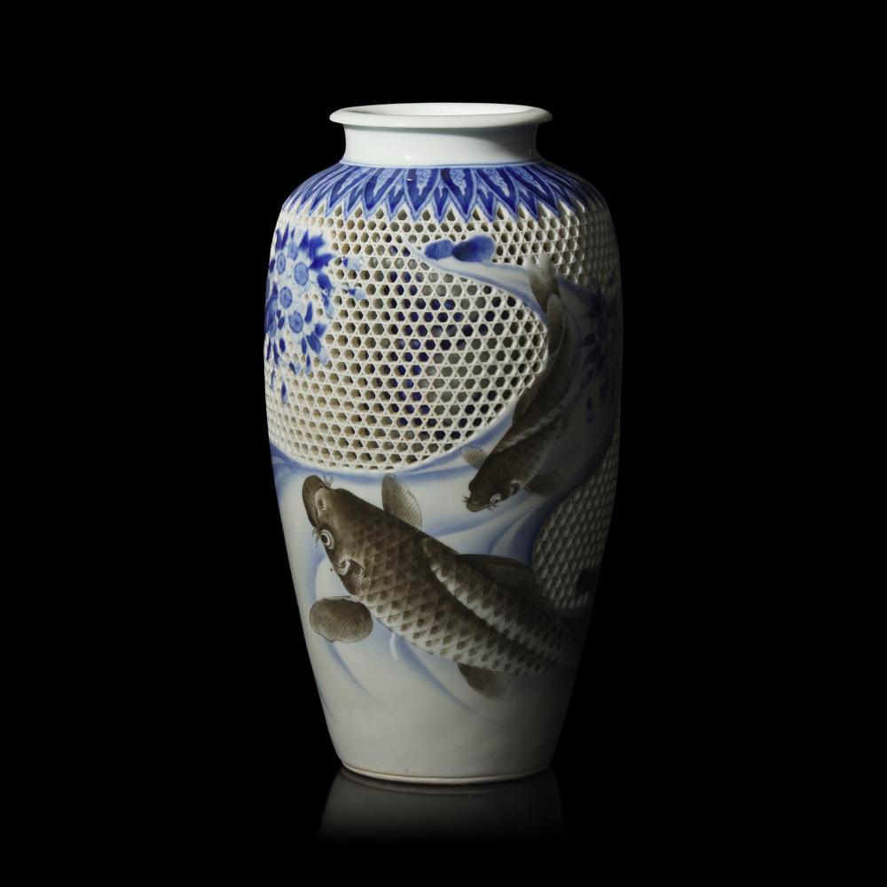 Blue-and-white porcelain vase with reticulated lattice pattern and koi fish decoration on a dark background.