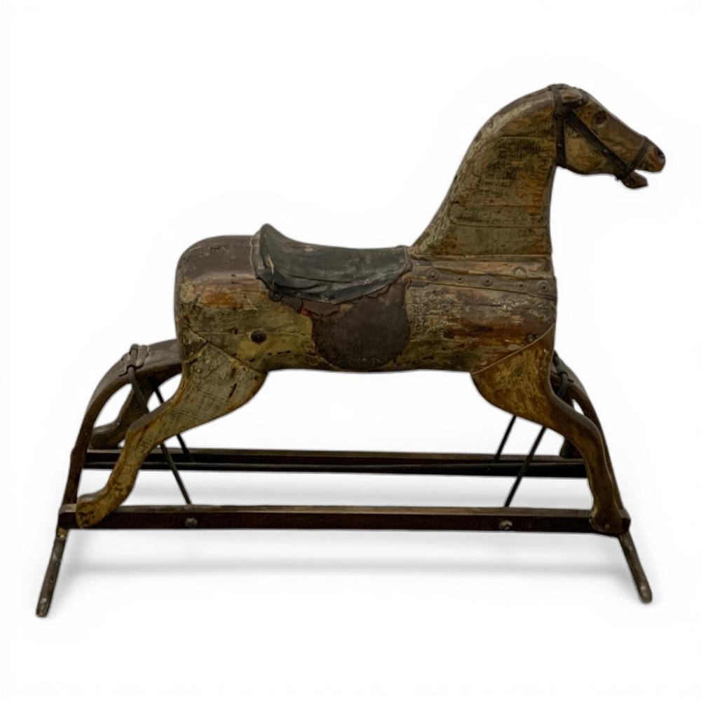 Carved wooden rocking horse with a brown and worn painted finish, shown in side view on a rocking stand.