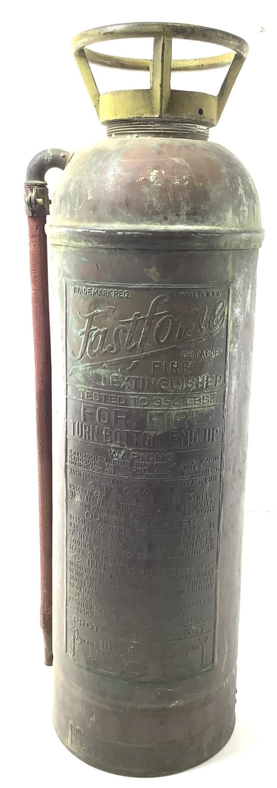 Antique-looking metal fire extinguisher with a brass top and hose connection, shown upright with embossed label text on the body.