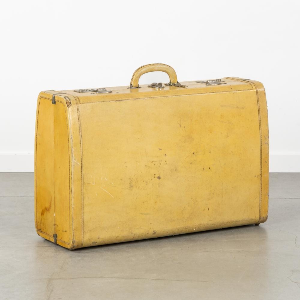 Yellow vintage leather suitcase with metal corner fittings and handle, shown on a light gray studio background.