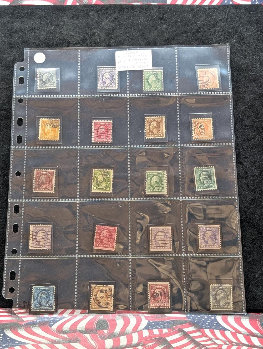 Photo of multiple vintage U.S. postage stamps arranged in rows inside a clear plastic stamp album page on a dark background.