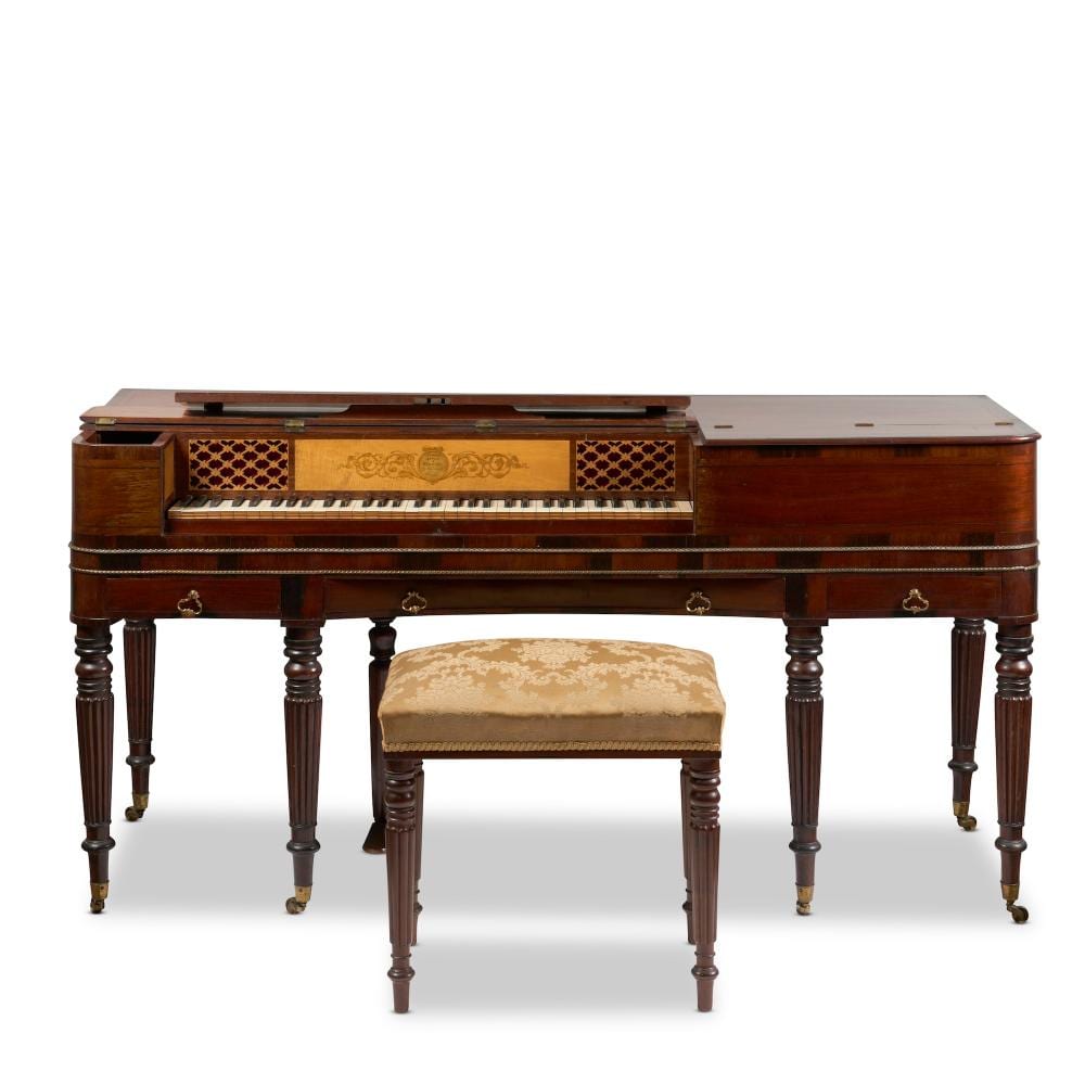 Mahogany square piano with a hinged fallboard open, showing keys and a decorated music panel; white background.