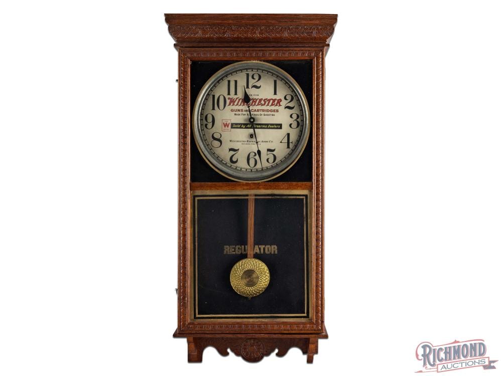 Front view of a vintage wooden wall clock with a round clock face labeled Winchester and a regulator panel below.