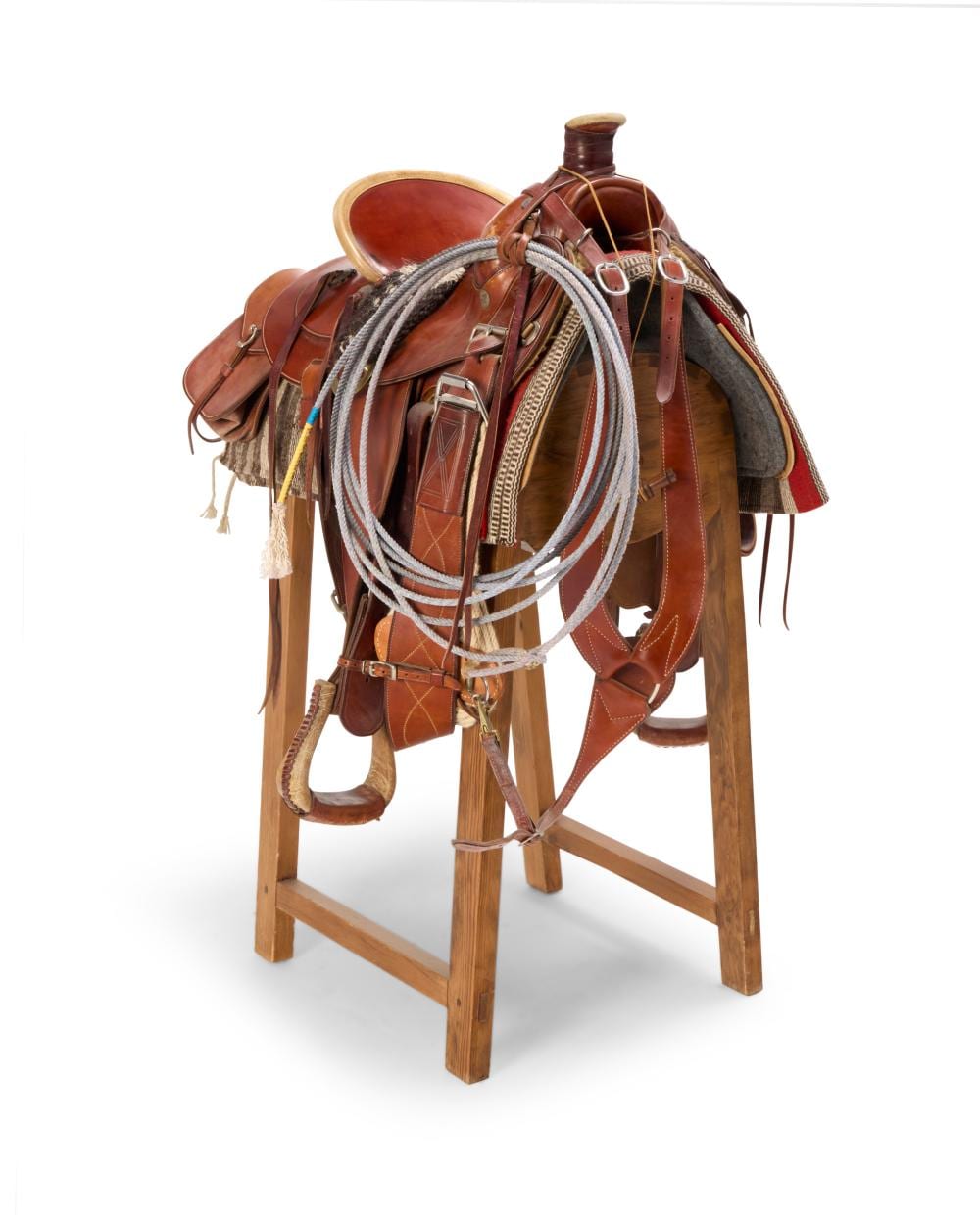 Brown western saddle displayed on a wooden stand with stirrups and braided reins draped over the saddle.