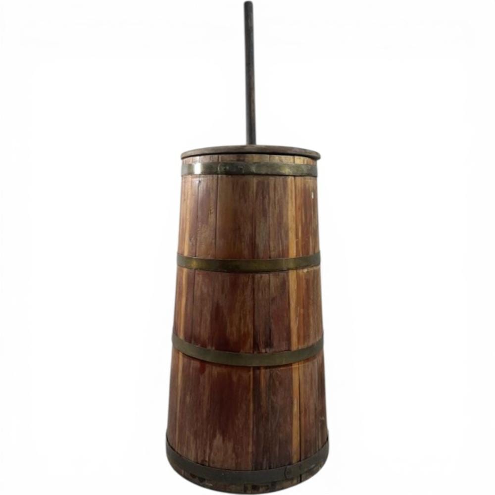 Small wooden butter churn with vertical handle and dark metal bands around the barrel.
