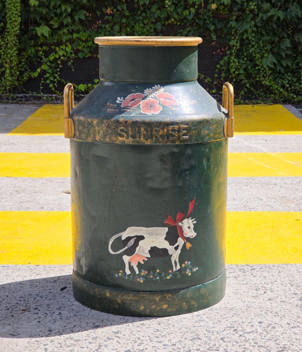 Green vintage milk can with arched handle straps, painted floral decoration and a cow with red head and flowers on the front.