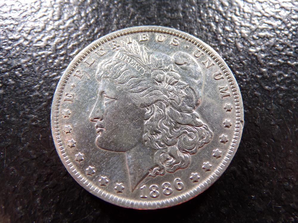 Close-up of an American silver dollar coin showing a profile of Lady Liberty and the date 1886.