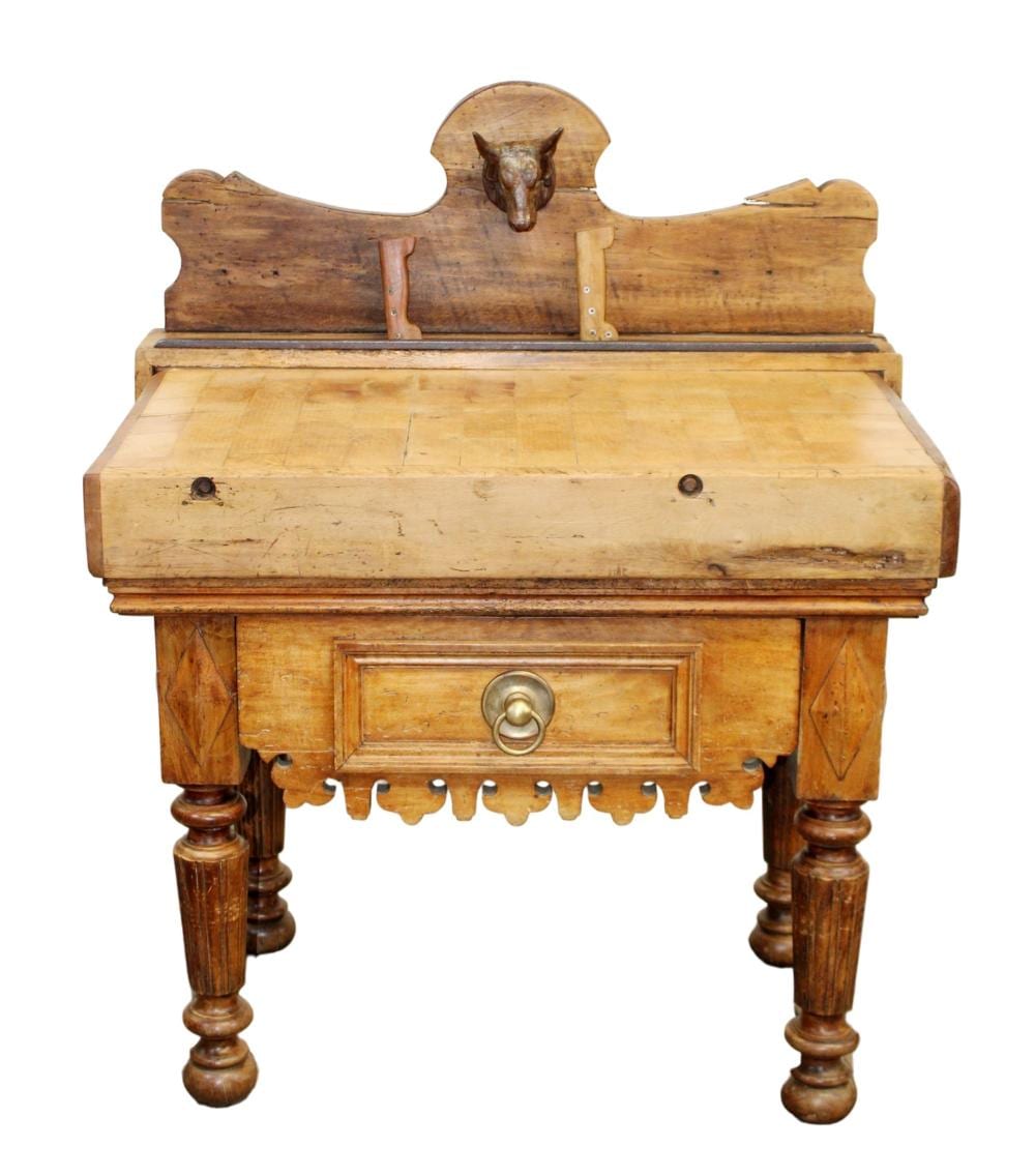 Antique wooden butcher block table with a bulls head ornament mounted on the back panel and a drawer front.