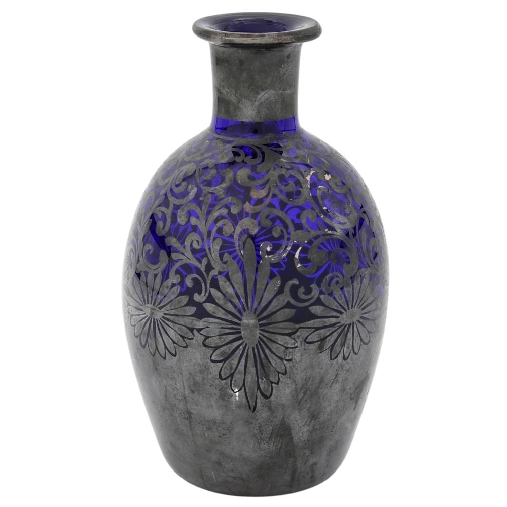 Cobalt blue glass decanter with an etched floral scroll pattern and a metal collar at the neck.