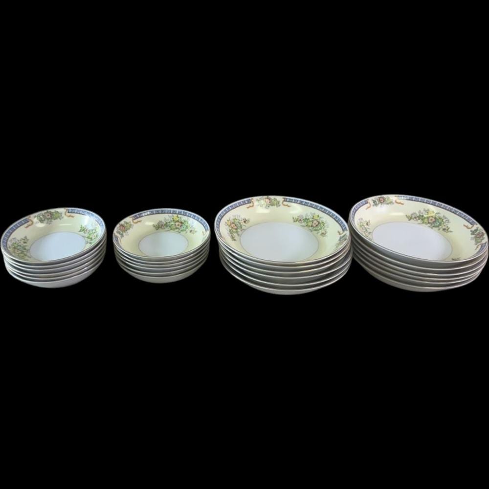 Stack of vintage porcelain bowls with blue rim border and floral sprays on cream background.