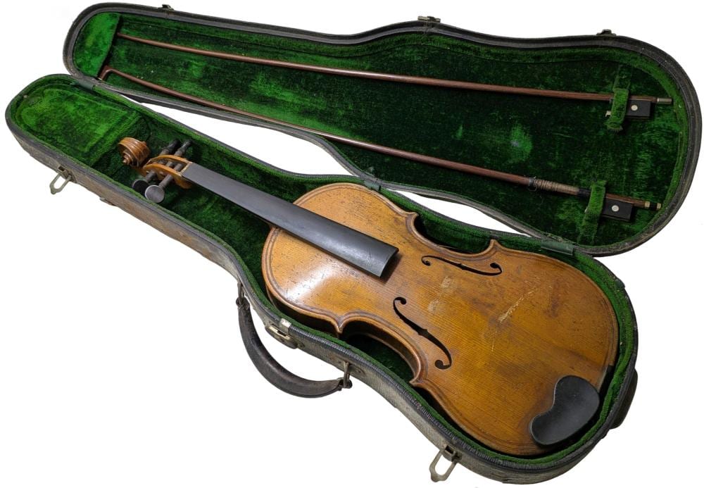 Wooden violin with strings and dark chinrest lying inside a green-lined hard case with two bows visible.