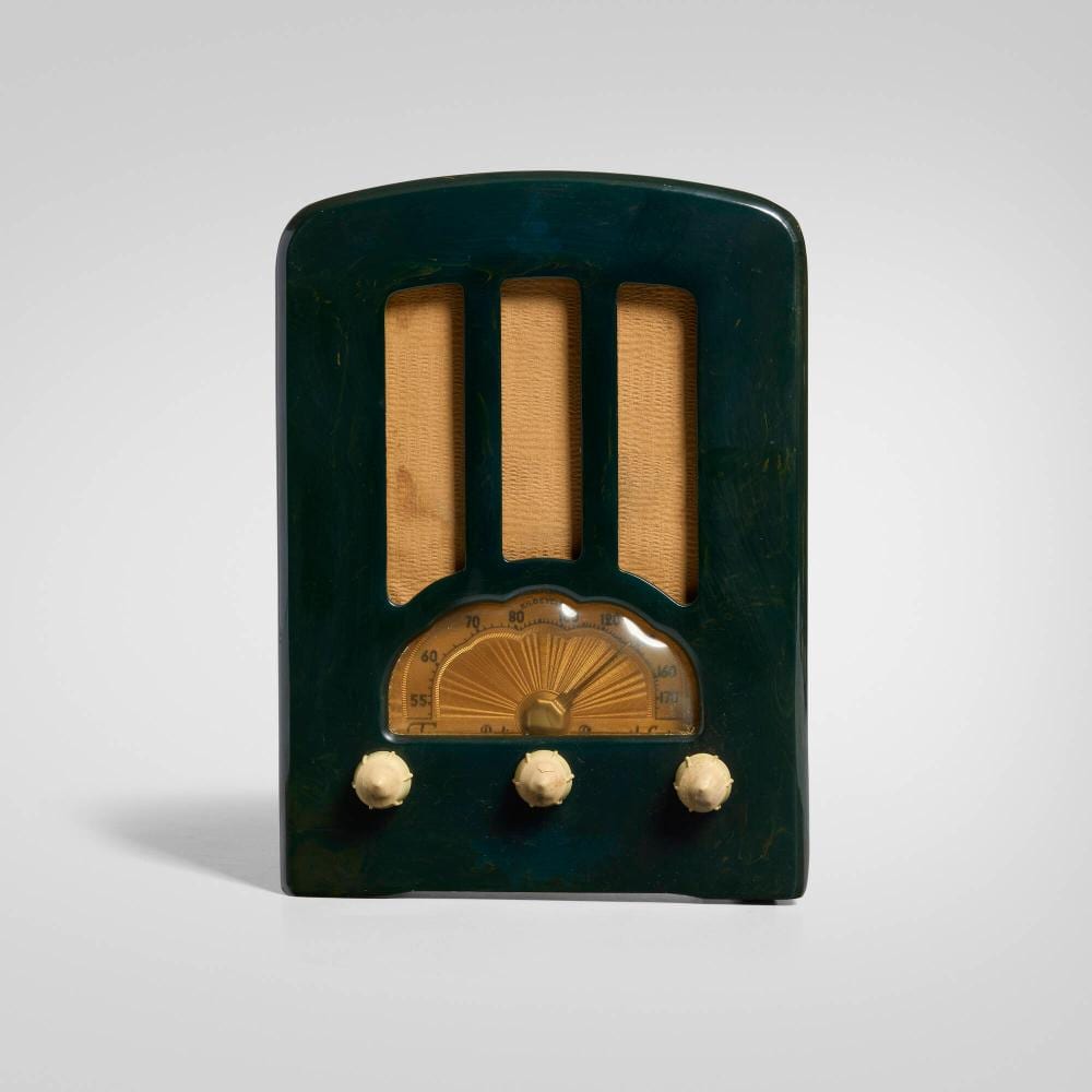 Green vintage radio cabinet with three vertical speaker-like openings and a gold tuning dial flanked by three knobs.
