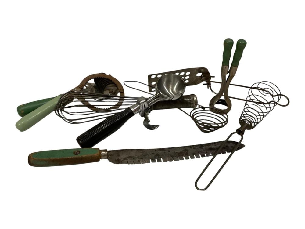 Assorted vintage kitchen utensils including a wire whisk, vegetable peeler, skimmer or strainer, and eggbeater-style tools.