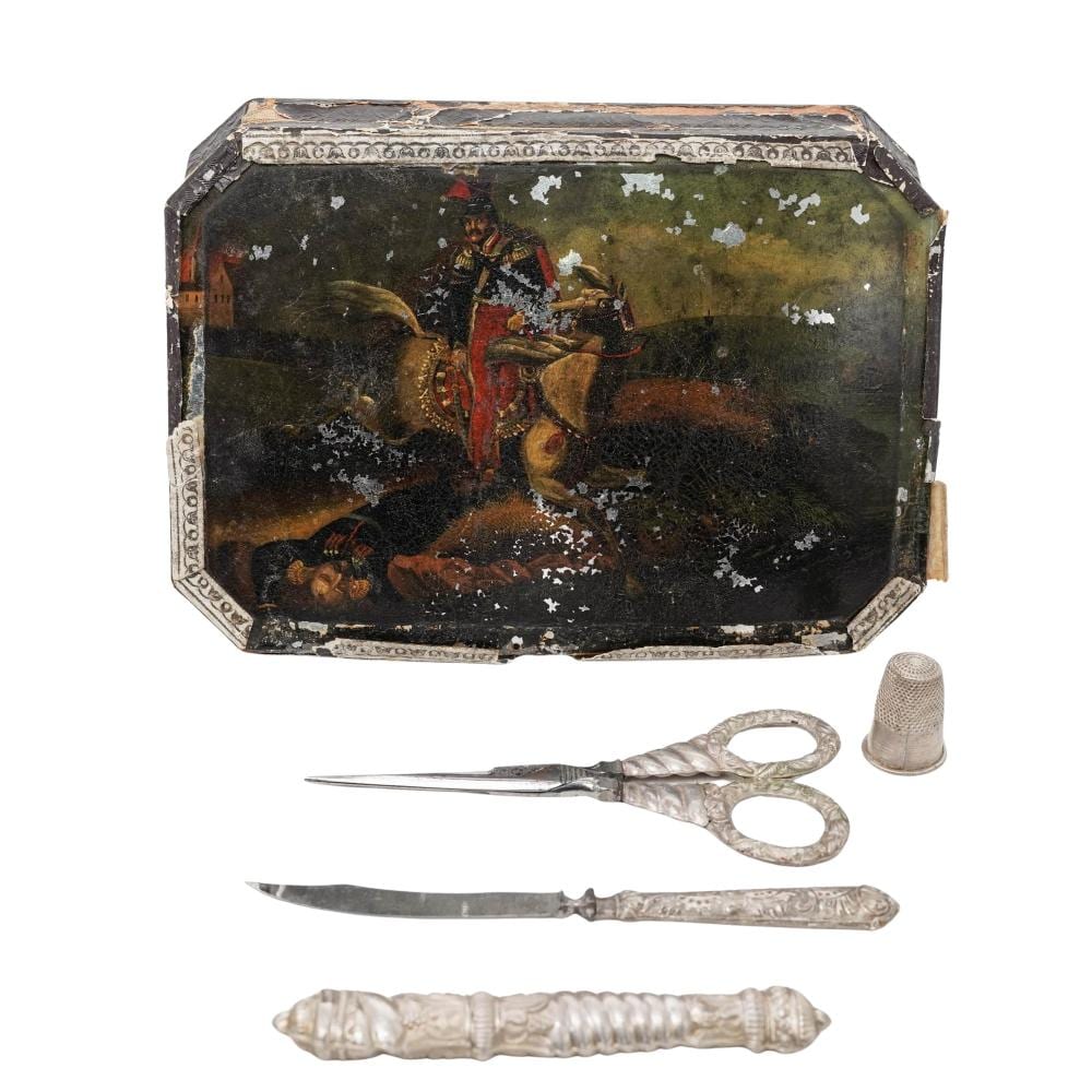 Antique-style metal sewing kit case with a painted scene on the lid, shown with scissors, thimble, and other sewing tools.