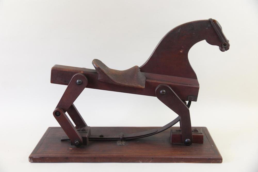 Wooden folk art rocking horse with a curved head and body, mounted on a rectangular base, shown in profile against a white background.
