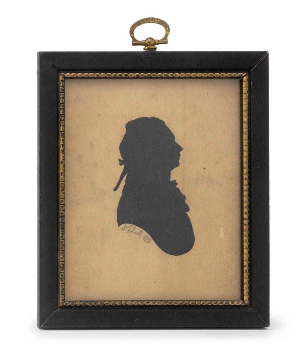 Framed black silhouette portrait of a person in profile, mounted on a light background with an ornate gold-toned border.