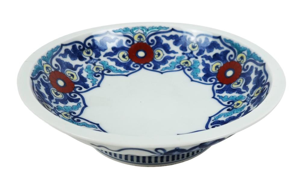 Glazed ceramic shallow bowl with blue and turquoise patterned rim and red circular medallion motifs on a white interior.