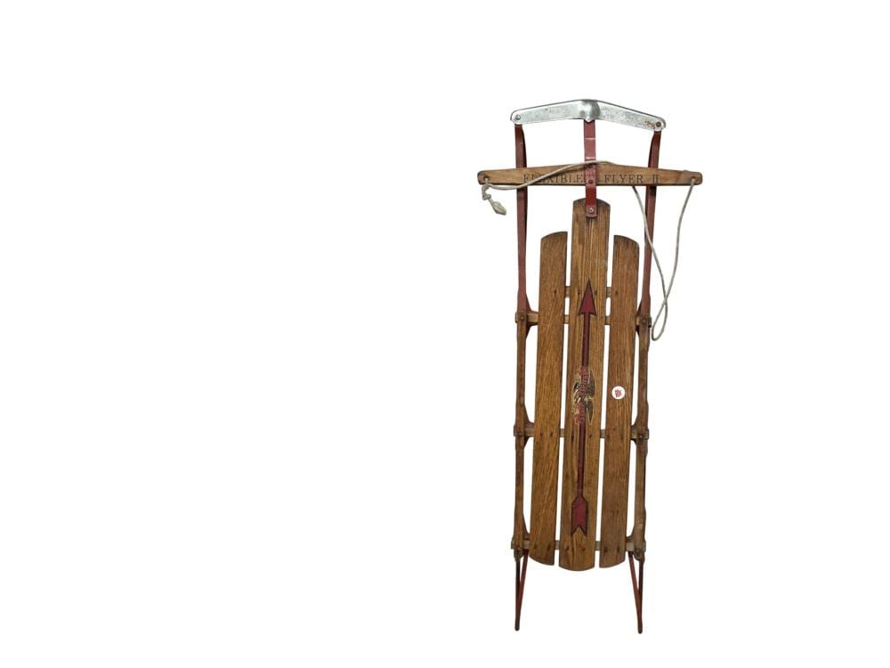 Wooden vintage sled with vertical slats, curved metal handle, and metal side fittings.