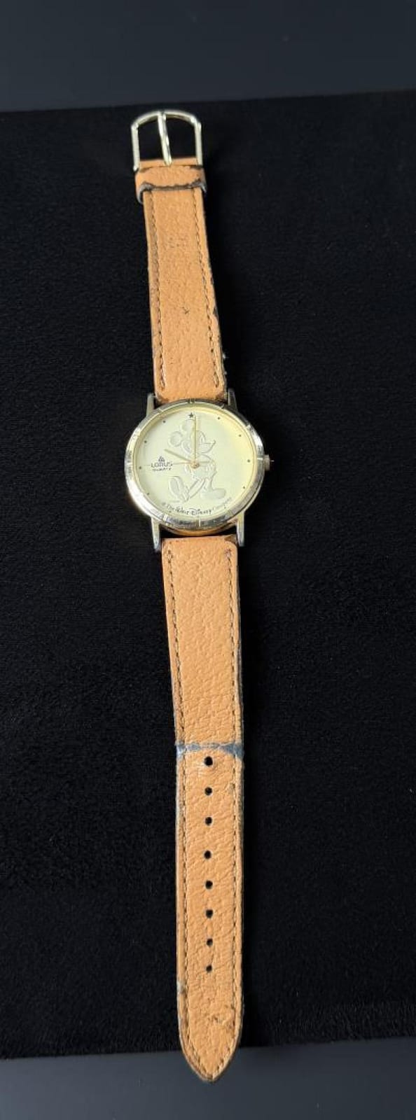 Small wristwatch with a tan leather strap and a round cream dial featuring a cartoon mouse figure and Mickey Mouse text.