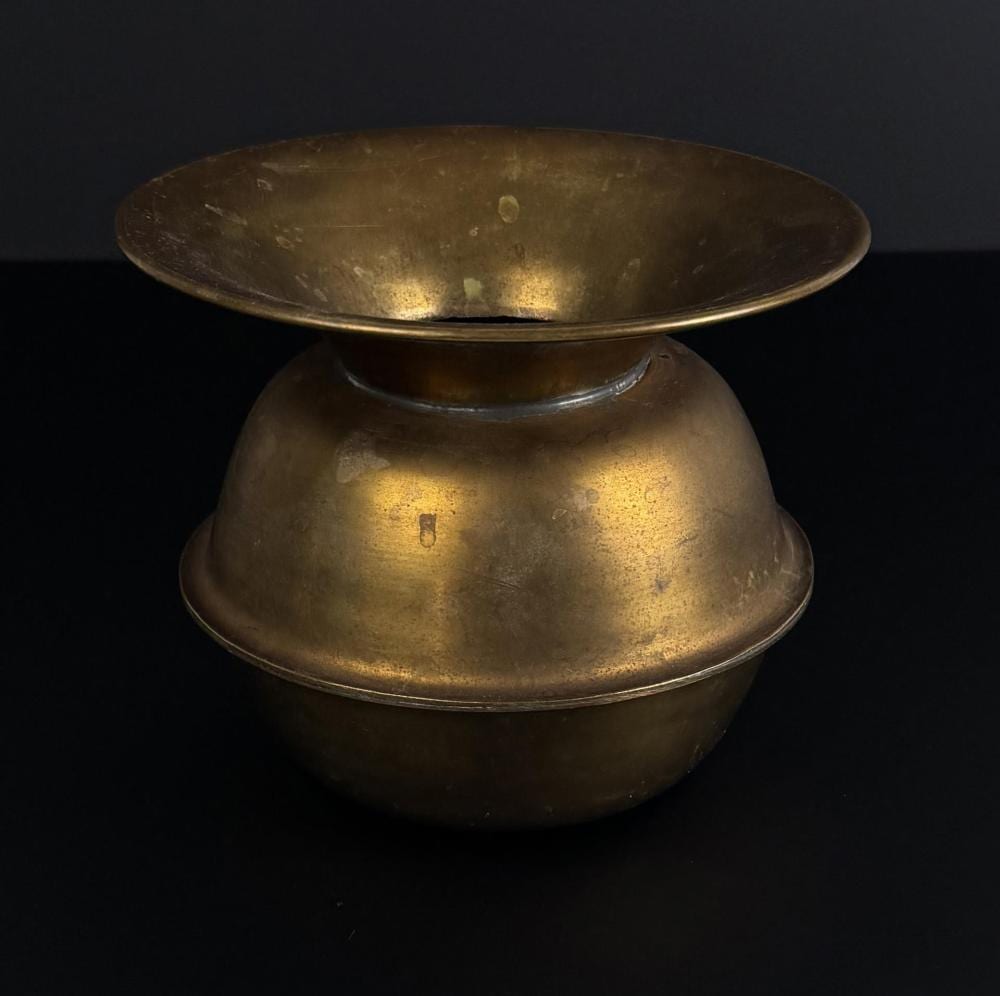 Antique brass spittoon with a flared bowl and rounded base on a dark background.