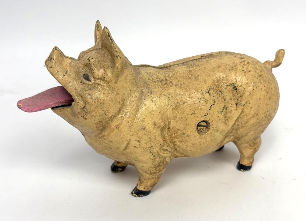 Painted piggy bank shaped like a pig with its head down and a coin slot on the side, with a pink tongue visible.