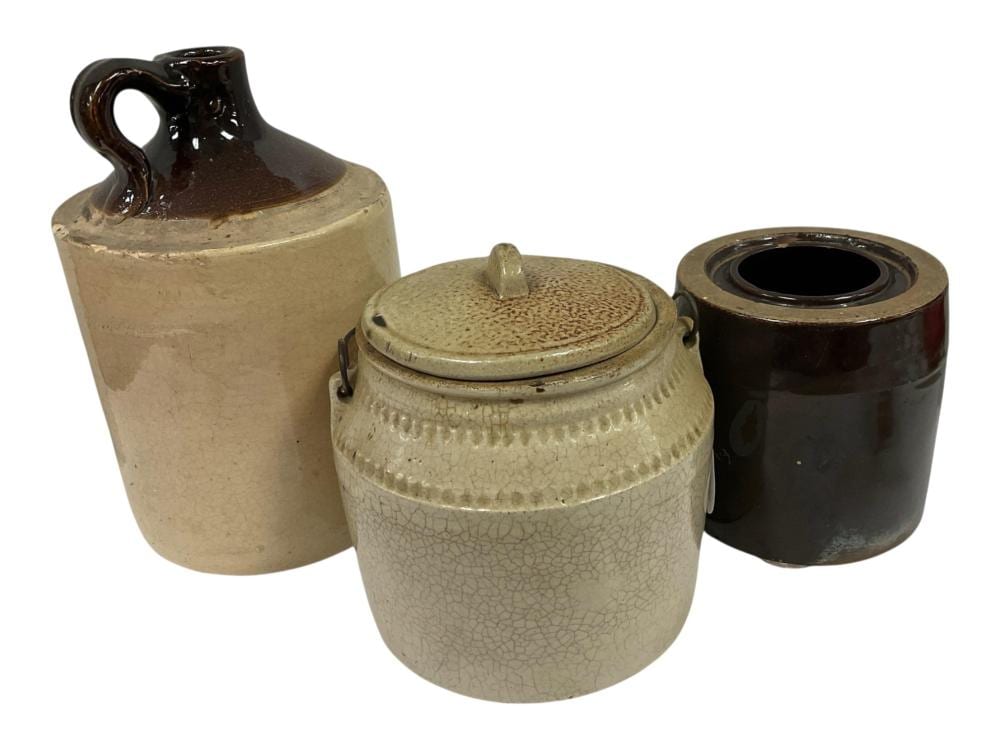 Three brown stoneware crocks and jugs, including a lidded crock with crackled glaze and two uncovered containers, on a white background.