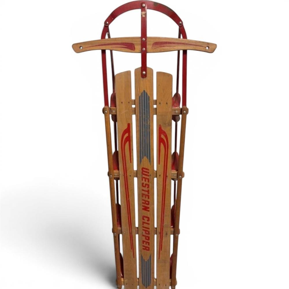 Wood and steel snow sled with a red frame and curved handle, featuring vertical slats with printed lettering in the center.