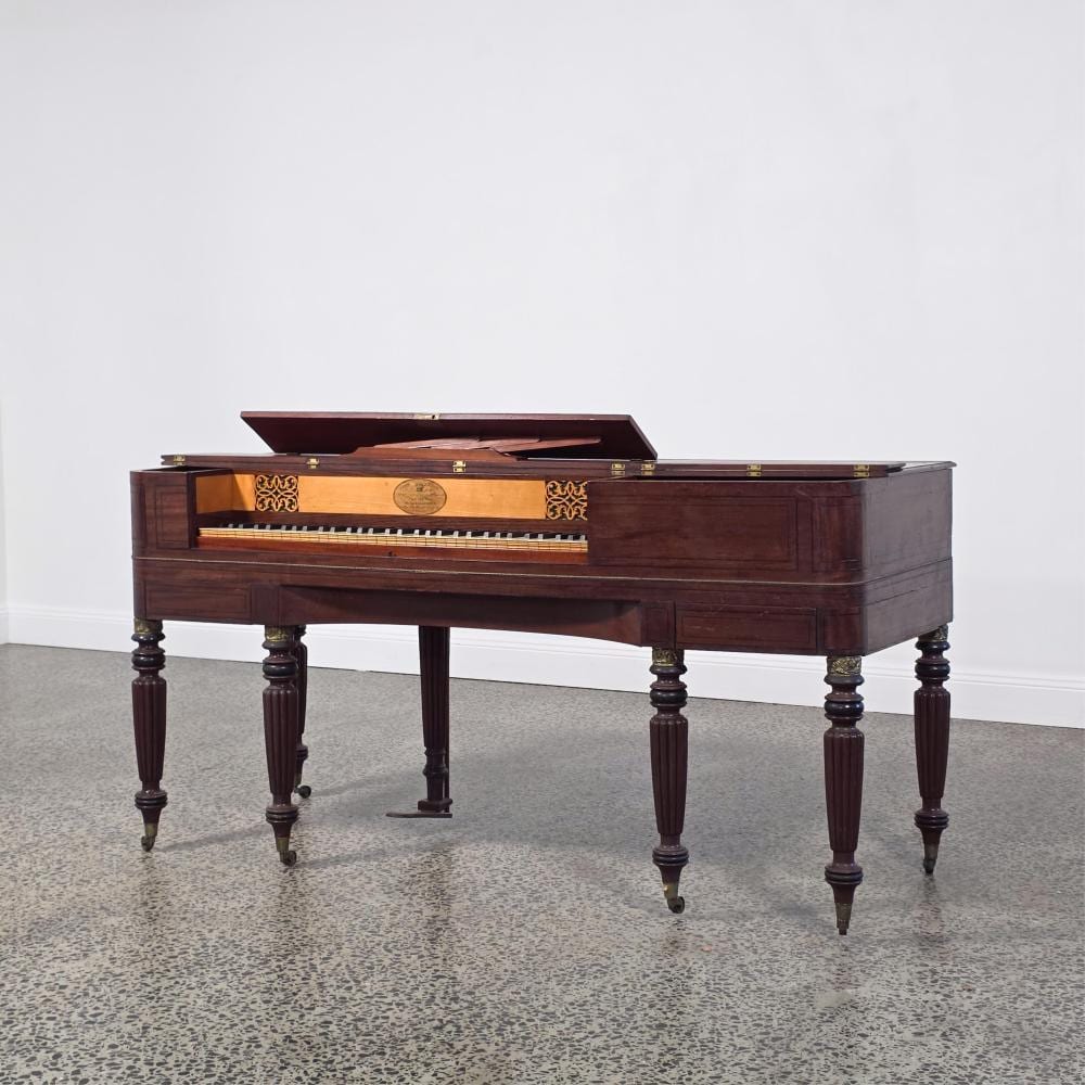 Mahogany square piano with its lid open, showing keys and brass details, supported on four turned legs.