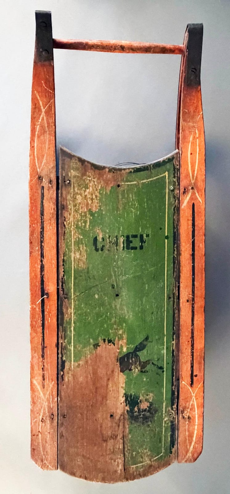 Small wooden runner sled with orange runners and black end panels, with a green painted seat panel showing the text “GO”