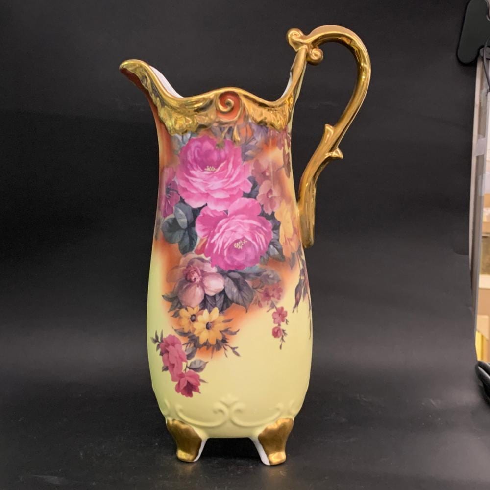 Porcelain floral pitcher with a gold handle and spout, painted with pink peonies and other colorful flowers on a pale yellow body.
