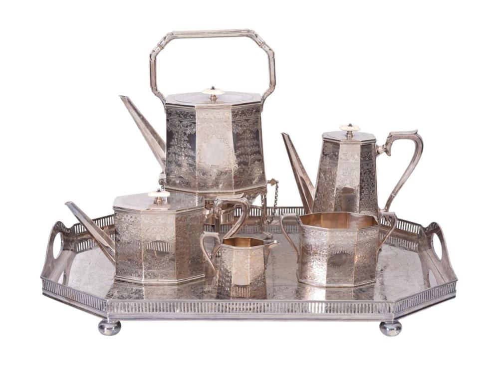 Five-piece silverplate tea service set with engraved pots and covered kettle on a matching tray, photographed on a white background.