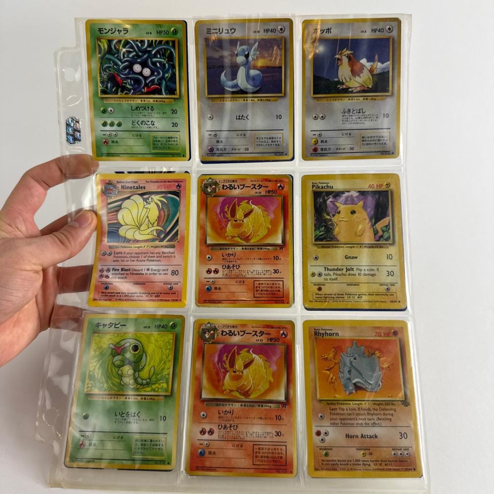 Hand holding a plastic card holder containing six Japanese Pokémon trading cards, including Pikachu and other creatures.