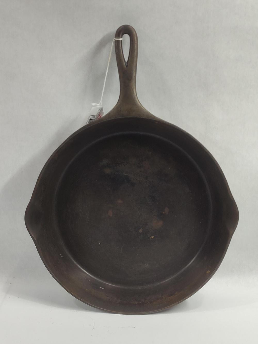 Cast iron skillet with dark patina and a loop handle shown from above on a white background.