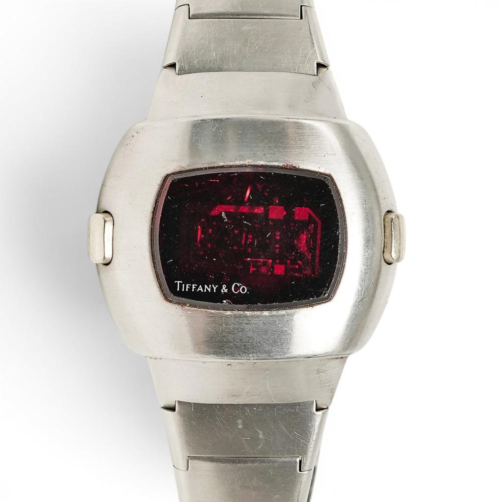 Close-up of a silver LED digital wristwatch with a black screen showing red illuminated time graphics and the “TIFFANY & CO.” logo.