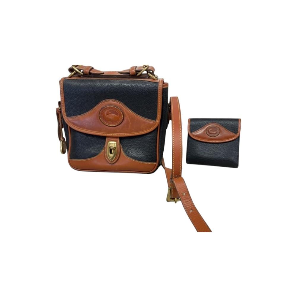Navy and brown leather crossbody bag with front flap and brass hardware, shown with a matching small wallet