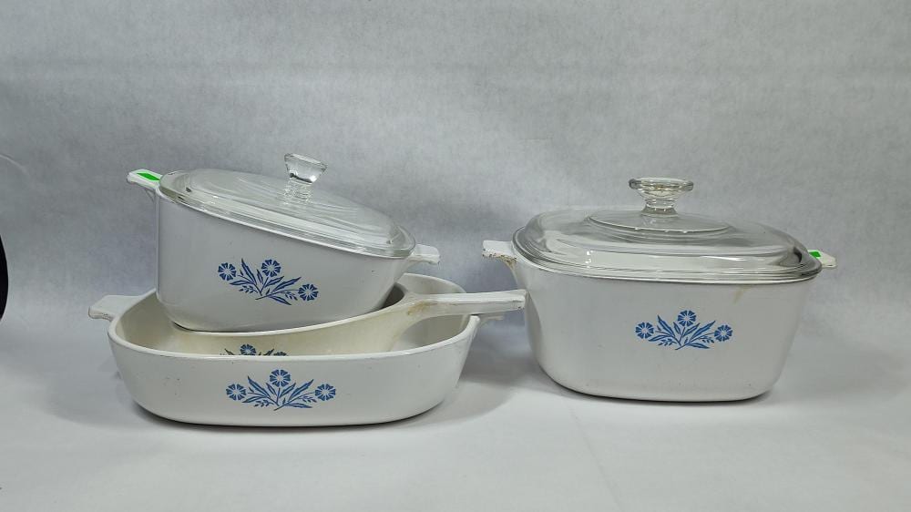 Set of white ceramic cookware with blue cornflower pattern, showing two lidded pots and an open casserole dish with glass lids.