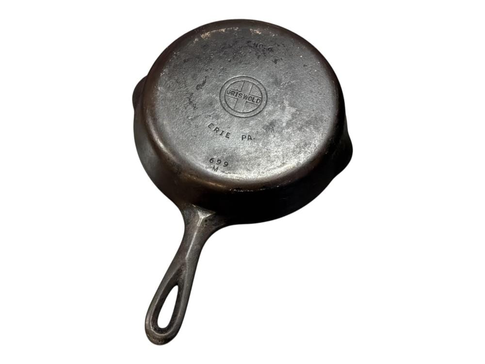Round cast iron skillet with a pouring spout and loop handle, showing a Griswold logo and markings on the underside.