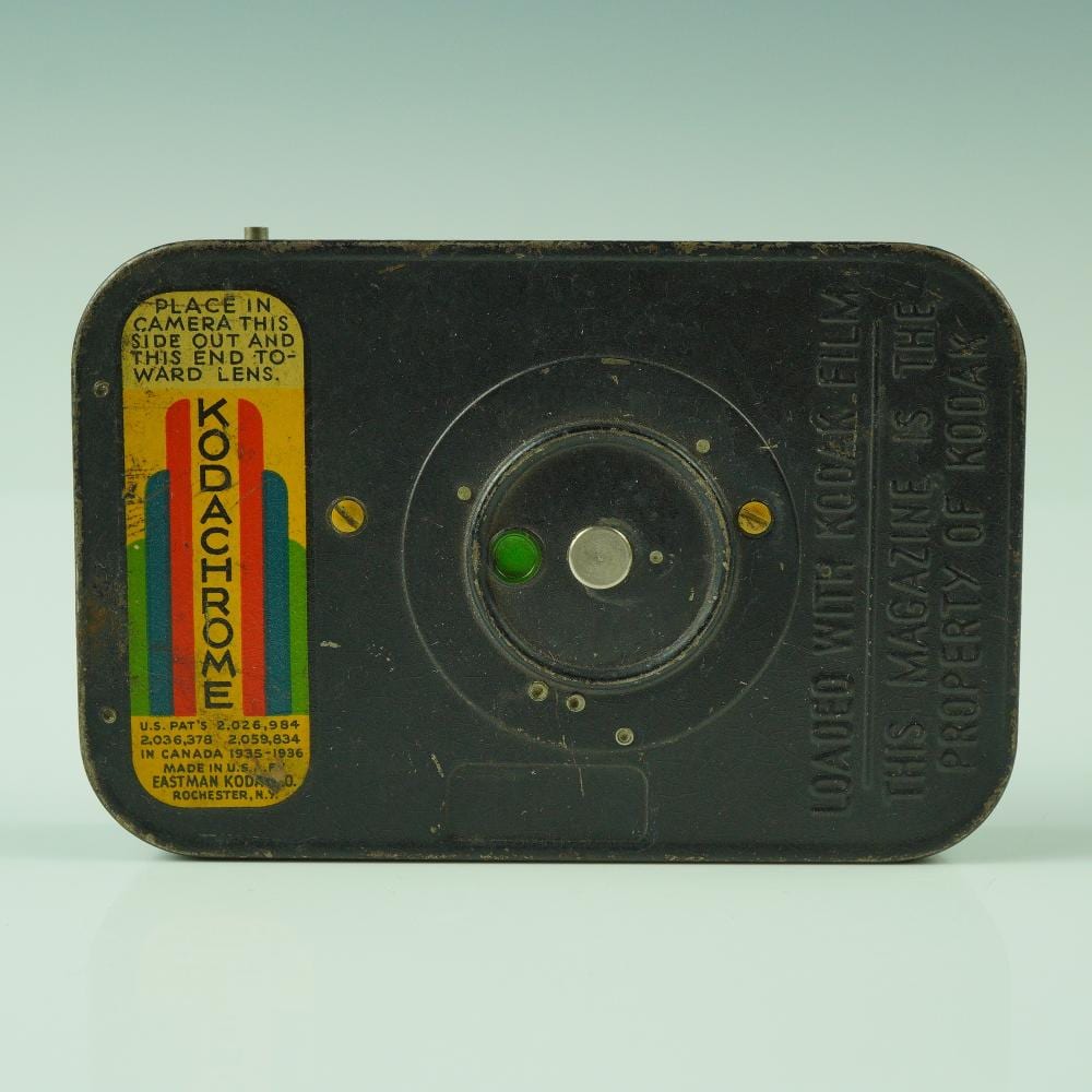 Vintage black Kodak Kodachrome 16mm film magazine container with circular window and “Kodachrome” label on the side.