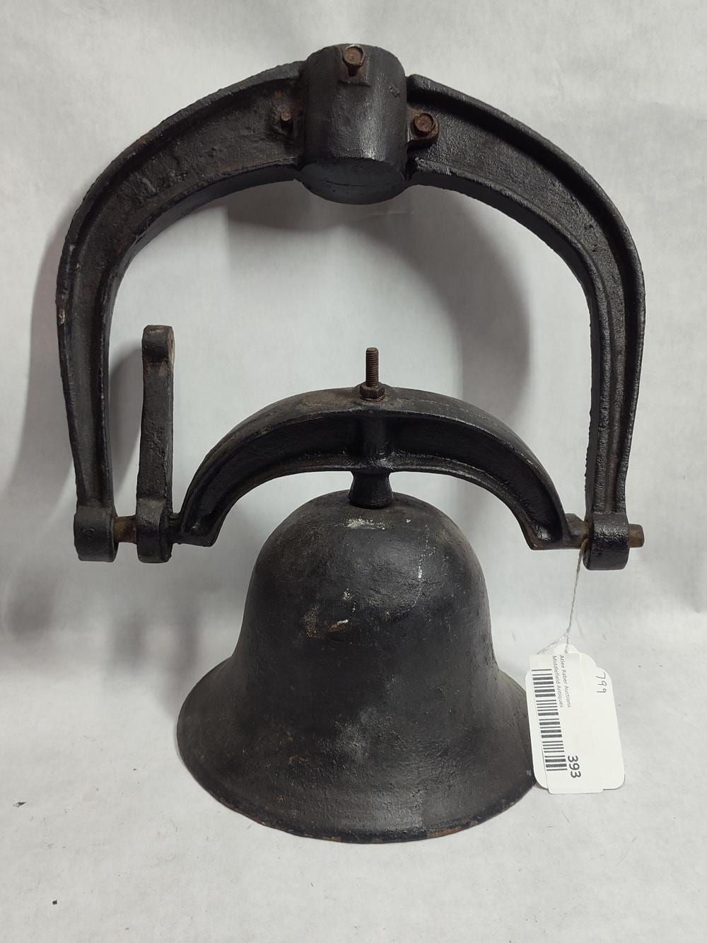 Black cast iron bell with arched handle frame and a threaded mounting stud, photographed on a light background.