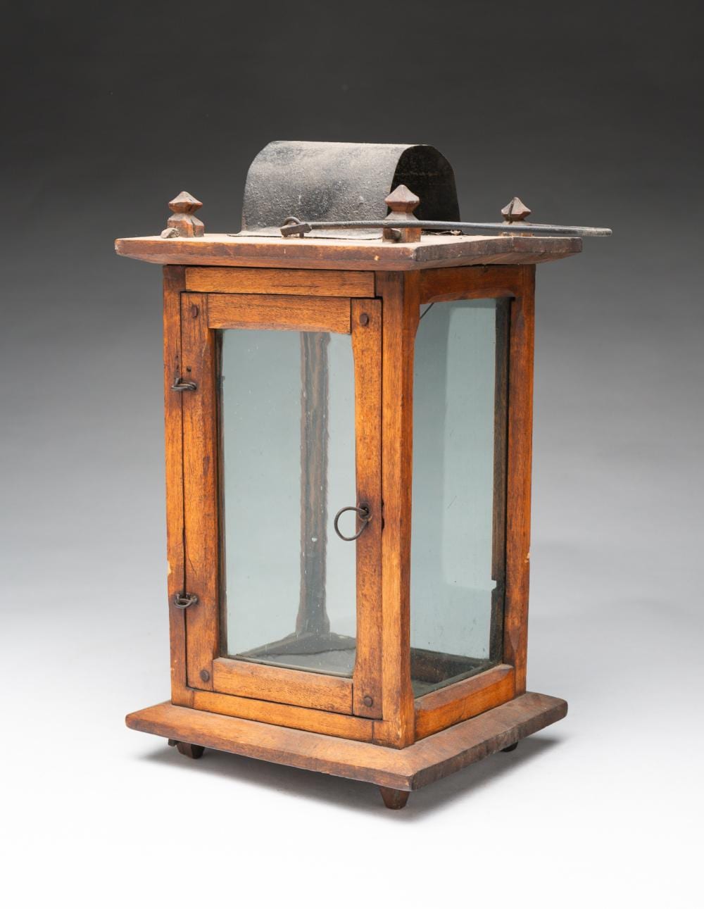 Wood barn lantern with a glass front panel and metal top, standing on a wooden base.