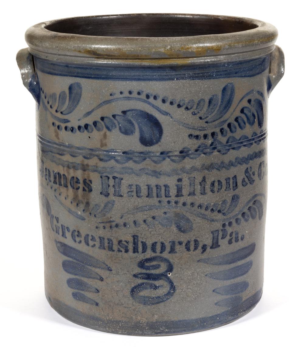 Stoneware crock with a wide rim and two side handles, decorated with blue slip bands and stylized letters.