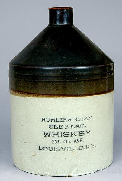 Small vintage stoneware whiskey jug with a dark neck and body, cream lower half, and printed label text including “HUMMLER & NULAN” and “LOUISVILLE, KY.”