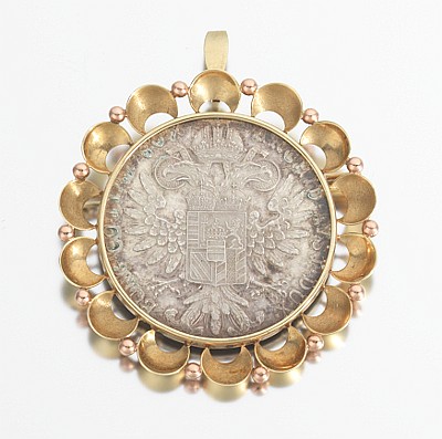 Round silver coin pendant set in a gold scalloped frame with small bead-like links around the edge and a top bail.