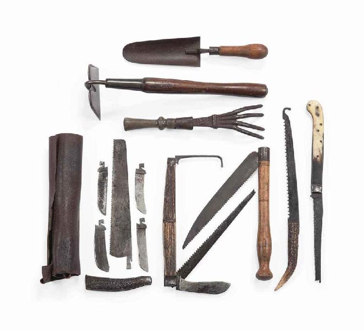 Group of vintage steel garden tools on a white background, including shovels, a hand hoe, and pruning saws with wooden handles.