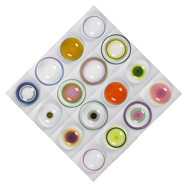 Top view of a square grid of colorful enamel-like circular domes in multiple colors on a light gray base.